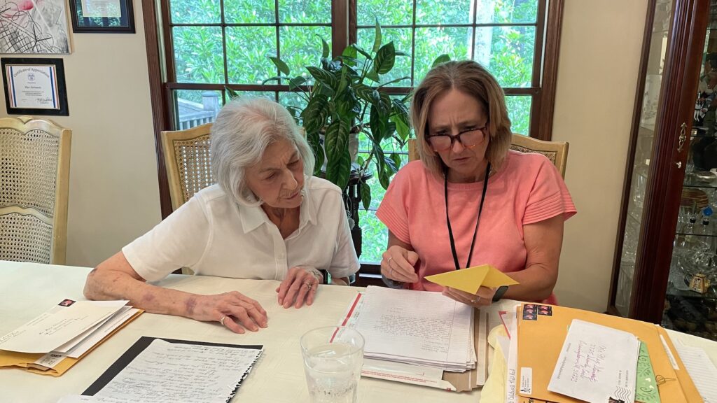 Envelope with gift inside, 2 women looking at it with other papers